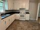 Functional kitchen featuring white cabinetry, black countertops, white appliances, and durable vinyl flooring at 5008 Delivau Dr, Charlotte, NC 28215