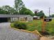 Charming home featuring a landscaped front yard, gravel driveway, covered carport and inviting front porch at 501 N Hawthorne St, Mount Holly, NC 28120