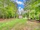 A quaint backyard shed nestled among lush trees, offering a serene and private outdoor space at 6758 Zion Church Rd, Concord, NC 28025