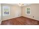 Bedroom with wood floors, a ceiling fan, and two windows offering natural light and green views at 6807 Woodfield Dr, Charlotte, NC 28215