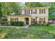 Charming two-story home with yellow siding, red shutters, and a brick entryway at 6807 Woodfield Dr, Charlotte, NC 28215