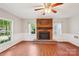 Well-lit living room boasts hardwood floors and a brick fireplace for a warm atmosphere at 6807 Woodfield Dr, Charlotte, NC 28215