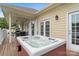 Outdoor jacuzzi area featuring a wooden deck, built-in hot tub, white siding, and outdoor lighting at 7471 Barfield Ln, Denver, NC 28037