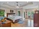 Bright main bedroom featuring hardwood floors, tray ceilings, a ceiling fan, and french doors to the outdoor area at 7471 Barfield Ln, Denver, NC 28037