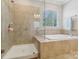 Bright bathroom with tiled shower, separate soaking tub, and a large window at 8200 Sunset Hill Rd, Waxhaw, NC 28173