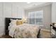 Cozy bedroom features paneled wall accents, a comfortable bed, and natural light from a window with wood flooring at 8200 Sunset Hill Rd, Waxhaw, NC 28173