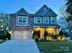 Exterior dusk view of home with manicured landscaping, a two-car garage, and illuminated front porch at 8200 Sunset Hill Rd, Waxhaw, NC 28173