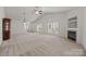 Open-concept living room with a fireplace, neutral carpet, and ample natural light from large windows at 8313 Carob Tree Ln, Charlotte, NC 28215