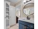 Updated bathroom featuring modern fixtures, navy vanity with marble countertop, and adjacent linen closet at 1030 Westbury Dr, Matthews, NC 28104