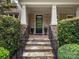 Stone steps lead to a covered front porch, complemented by classic columns and lush landscaping at 1030 Westbury Dr, Matthews, NC 28104