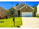 A brick home featuring a 2-car garage, well-manicured lawn, and blooming garden beds at 1680 Beleek Ridge Ln, Clover, SC 29710