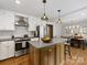 Open kitchen showcasing a central island, stainless steel appliances, white cabinets and breakfast bar overlooking dining area at 1714 Edgewater Dr, Charlotte, NC 28210