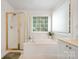 Well-lit bathroom featuring a garden tub, shower, and large window, creating a spa-like atmosphere for relaxation at 2620 Shady Reach Ln, Charlotte, NC 28214