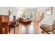 Bright living room with wood floors, a comfortable lounge chair, piano, and staircase, creating an inviting and stylish space at 2620 Shady Reach Ln, Charlotte, NC 28214