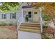 Welcoming front porch with natural wood steps, a cheerful yellow door, and a beautifully painted gray brick home at 3320 Eastwood Dr, Charlotte, NC 28205