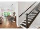 Entryway staircase with dark wood and iron banister, leading to the kitchen with barstool seating and modern lighting at 4902 Looking Glass Trl, Denver, NC 28037
