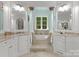 Luxurious bathroom with dual vanities, decorative columns, a soaking tub, and natural light at 5030 Hardison Rd, Charlotte, NC 28226