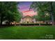 Stately home with manicured lawn, mature trees, and impressive architectural details at sunset at 5030 Hardison Rd, Charlotte, NC 28226