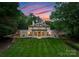 Beautiful home with lush green lawn in front, framed by mature trees against colorful sky at 5030 Hardison Rd, Charlotte, NC 28226