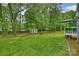 Lush green backyard featuring a small shed and deck, surrounded by mature trees and greenery at 616 Trailing Rock Dr, Charlotte, NC 28214