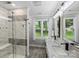 The spacious bathroom features a glass enclosed shower, a double sink vanity, and a window at 616 Trailing Rock Dr, Charlotte, NC 28214
