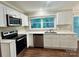 Modern kitchen featuring stainless steel appliances, white cabinetry, and a large window overlooking a green yard at 7401 Kinsmore Ln, Charlotte, NC 28269