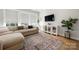 Bright living room with a beige sectional sofa, stylish rug, and a modern entertainment center with a large screen TV at 8107 Houser St, Cornelius, NC 28031