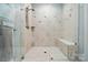 Modern walk-in shower with custom tile, glass enclosure, and a built-in bench provide a spa-like experience at 8473 Bing Cherry Dr, Denver, NC 28037
