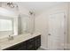 Bright bathroom featuring a double sink vanity, large mirror, and white paneled door at 10417 Ebbets Rd, Charlotte, NC 28273