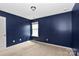 Cozy bedroom features neutral carpet and window, bathed in soft, natural light and dark blue walls at 10417 Ebbets Rd, Charlotte, NC 28273