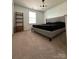 A modern bedroom with a large bed, shelf, window, and plush carpeting at 10417 Ebbets Rd, Charlotte, NC 28273