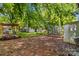 Spacious backyard featuring a brick patio, greenhouse, storage sheds, and lush greenery at 119 Wiley Ave, Salisbury, NC 28144