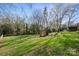 Expansive backyard featuring lush grass, mature trees, a charming wooden playset, and an American flag at 1628 Starbrook Dr, Charlotte, NC 28210