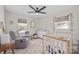 Bright bedroom featuring a comfortable glider, crib, dresser, and large windows, offering a serene atmosphere at 1628 Starbrook Dr, Charlotte, NC 28210
