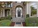 Inviting stone entryway with elegant black door, flanked by lush greenery and stylish lanterns at 18730 Floyd Ct, Davidson, NC 28036