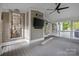 Screened-in porch with a ceiling fan, television, and comfortable seating at 18730 Floyd Ct, Davidson, NC 28036
