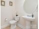 Stylish powder room with a pedestal sink, round mirror, and elegant decor, perfect for guests at 3925 Tokay Ln, Fort Mill, SC 29707