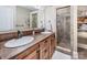 Bathroom with double sinks, wood vanity, tiled shower with glass door, and linen closet at 4600 Spicewood Dr, Charlotte, NC 28227