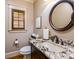 Bathroom featuring a granite countertop, dark wood cabinets, and a round mirror at 4600 Spicewood Dr, Charlotte, NC 28227