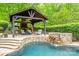 Outdoor entertainment area with a brick fireplace, grill, covered seating, and a pool waterfall at 4600 Spicewood Dr, Charlotte, NC 28227
