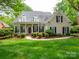 Charming home featuring a covered front porch, dark shutters, and lush landscaping at 7716 Seton House Ln, Charlotte, NC 28277
