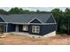 Dark blue new construction home with white window frames and brick base, surrounded by large green trees at 85 Cornerstone Dr, Taylorsville, NC 28681