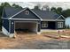 New construction home features a dark blue exterior, white brick base, a garage, and a modern roof line at 85 Cornerstone Dr, Taylorsville, NC 28681