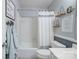 Neutral bathroom with a shower-tub combo with a white shower curtain and decor shelving at 9707 Enid Ln, Matthews, NC 28105
