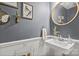 Stylish powder room features a pedestal sink, round mirror and attractive wall decor at 9707 Enid Ln, Matthews, NC 28105