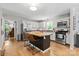 Modern kitchen featuring a center island with seating, stainless steel appliances, and light wood floors at 9707 Enid Ln, Matthews, NC 28105