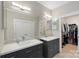 Bright bathroom featuring dual sinks, vanity storage, and a view into the closet at 1004 Berwick Ct, Waxhaw, NC 28173
