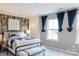 A staged bedroom with an accent wall and neutral tones and window at 12017 Grinstead Ln # 301, Charlotte, NC 28278