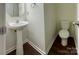 Compact half bath features a pedestal sink and matching white toilet at 12713 Frank Wiley Ln, Charlotte, NC 28278