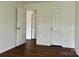 A light-filled bedroom featuring multiple doors and elegant dark hardwood flooring at 12713 Frank Wiley Ln, Charlotte, NC 28278